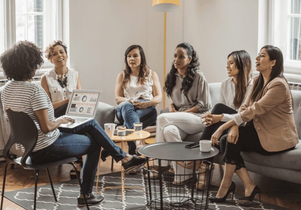 Women participating in a group coaching session discussing business growth and economic empowerment in a collaborative setting